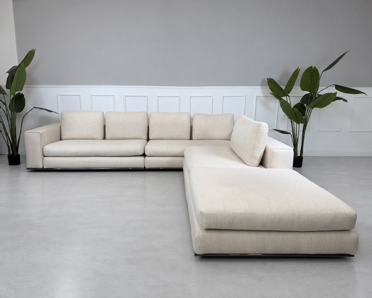 Gebrauchtes beiges Minotti Hamilton Designer Stoff Ecksofa vor einer Wand, stilvoll und modern eingerichtet.