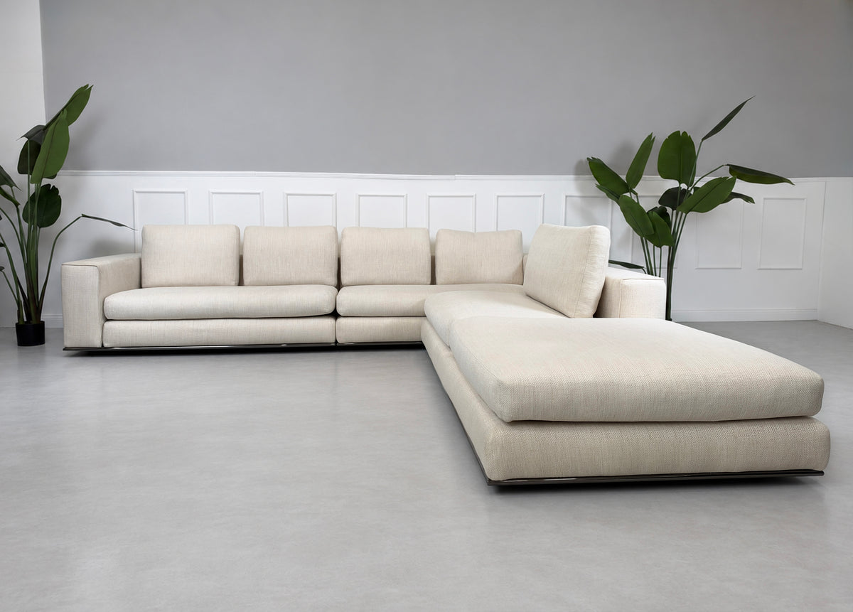 Gebrauchtes beiges Minotti Hamilton Designer Stoff Ecksofa vor einer Wand, stilvoll und modern eingerichtet.