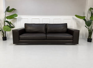 Gebrauchtes braunes Minotti Hamilton Designer Leder Sofa vor einer Wand, stilvoll und modern eingerichtet.
