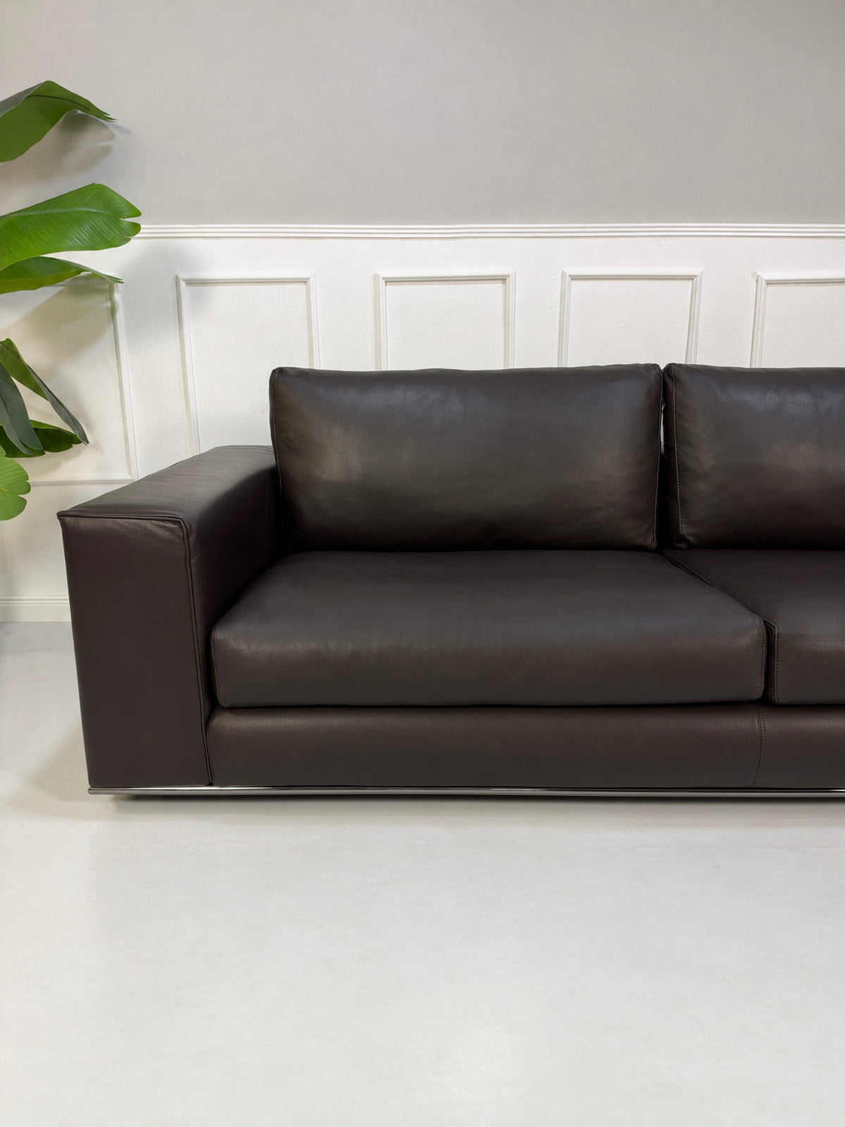 Gebrauchtes braunes Minotti Hamilton Designer Leder Sofa vor einer Wand, stilvoll und modern eingerichtet.
