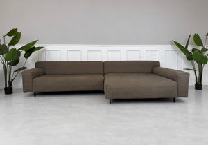 Gebrauchtes braunes Rolf Benz Grata Designer Stoff Ecksofa vor einer Wand, stilvoll und modern eingerichtet.