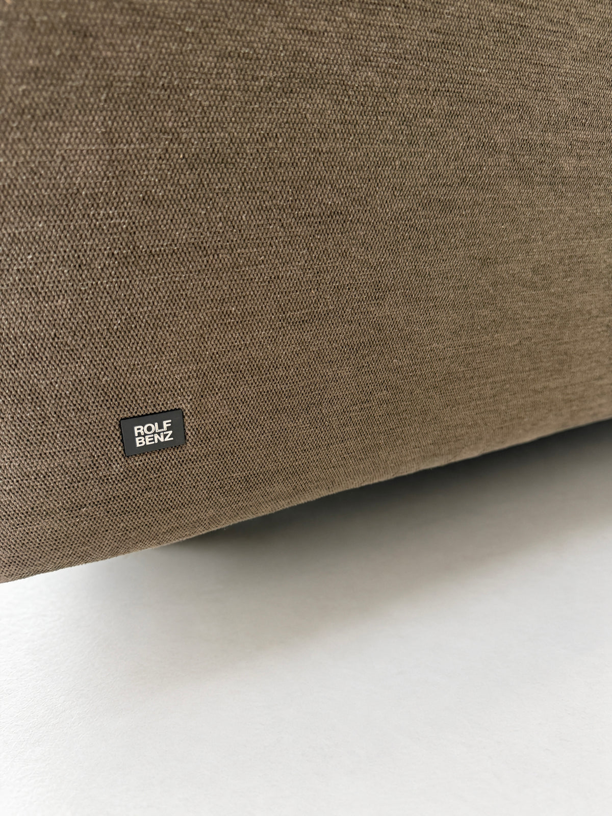 Gebrauchtes braunes Rolf Benz Grata Designer Stoff Ecksofa vor einer Wand, stilvoll und modern eingerichtet.