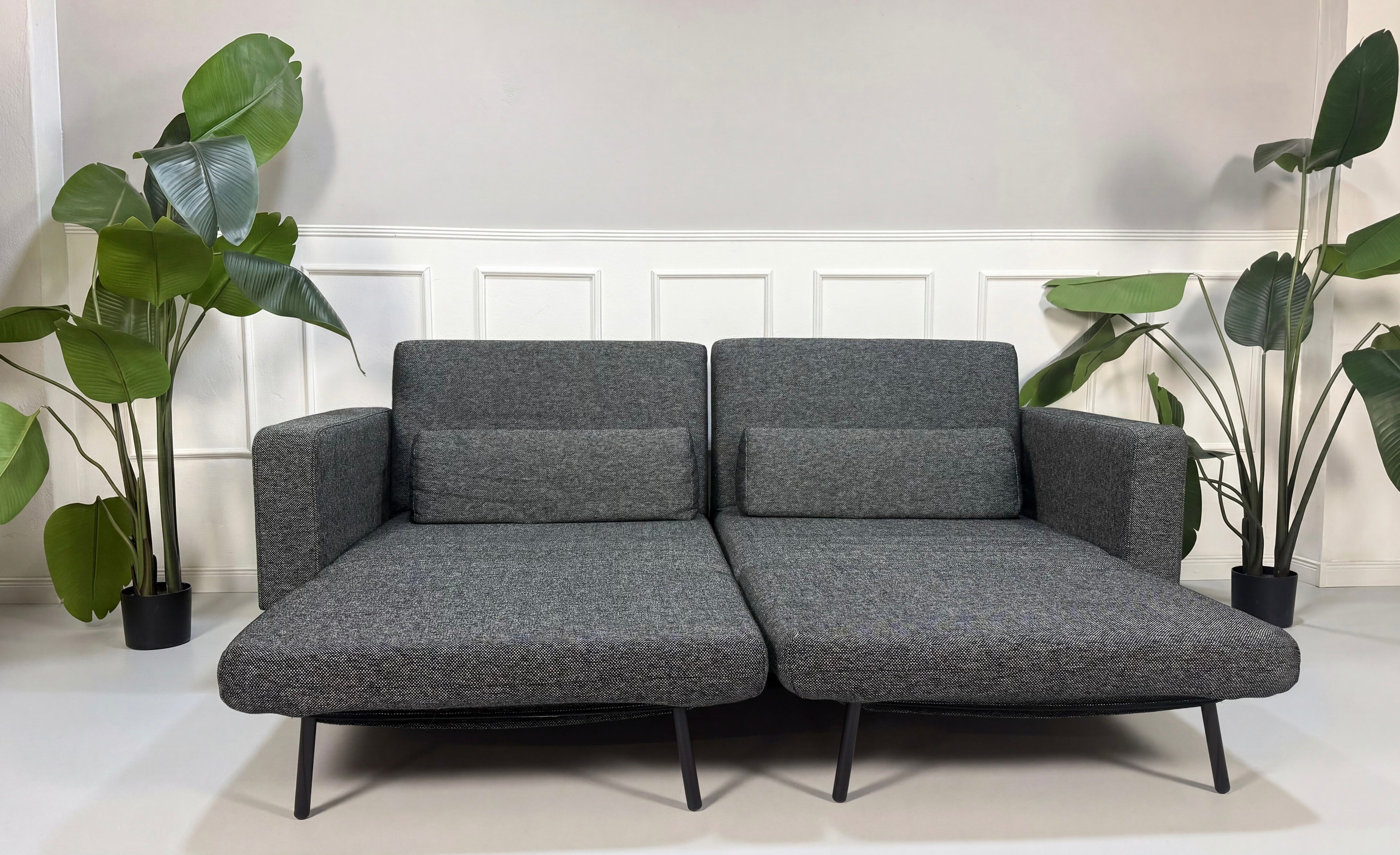 Gebrauchtes graues Studio Copenhagen Copperfield Designer Stoff Sofa vor einer Wand, stilvoll und modern eingerichtet.
