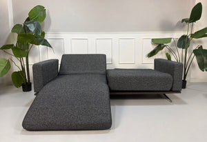 Gebrauchtes graues Studio Copenhagen Copperfield Designer Stoff Sofa vor einer Wand, stilvoll und modern eingerichtet.