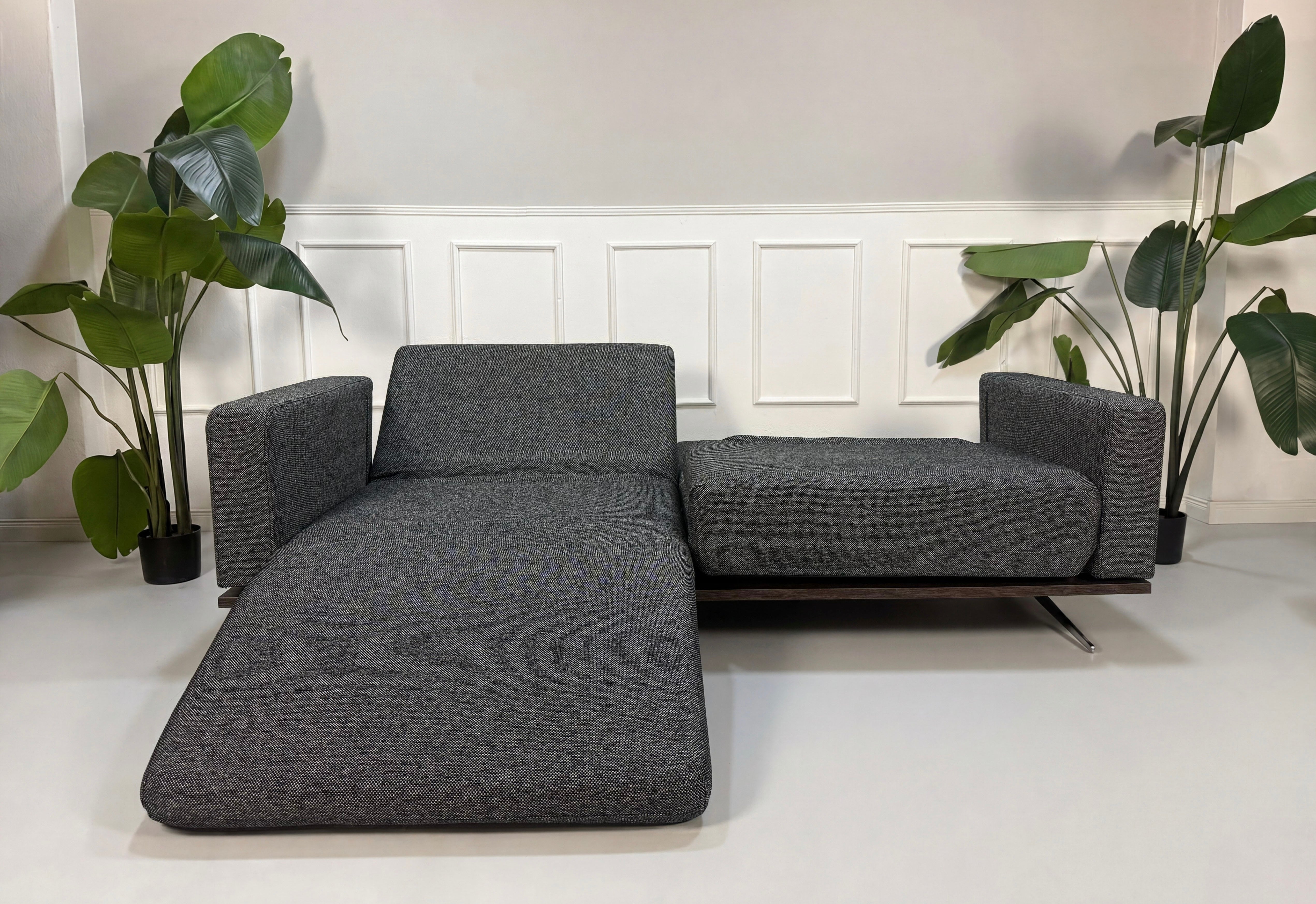 Gebrauchtes graues Studio Copenhagen Copperfield Designer Stoff Sofa vor einer Wand, stilvoll und modern eingerichtet.