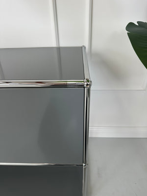 Gebrauchtes USM Haller Sideboard Regal in der Farbe Grau vor einer Wand, stilvoll und modern eingerichtet.