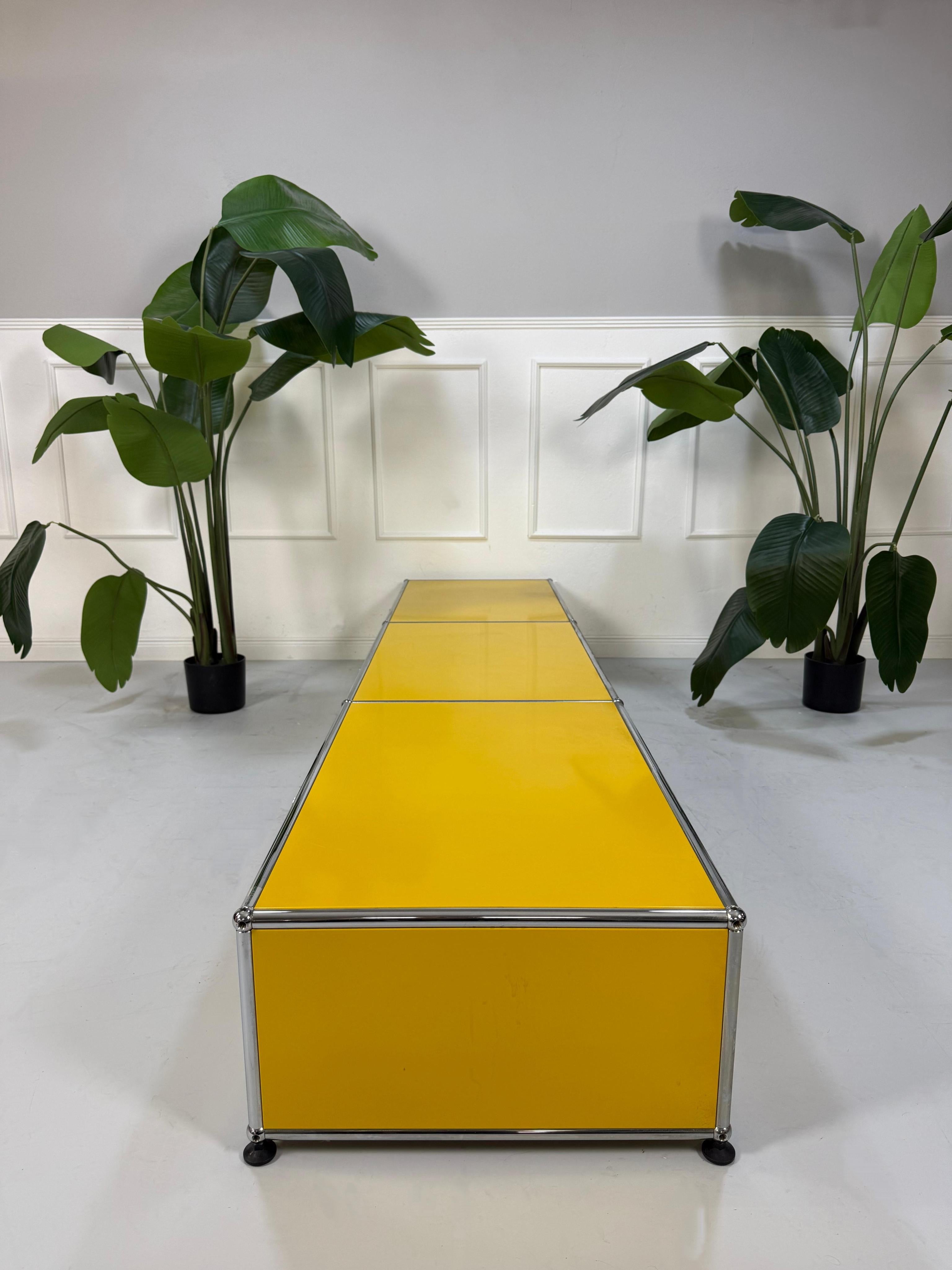 Gebrauchtes gelbes TV USM Haller Lowboard vor einer Wand, stilvoll und modern eingerichtet.
