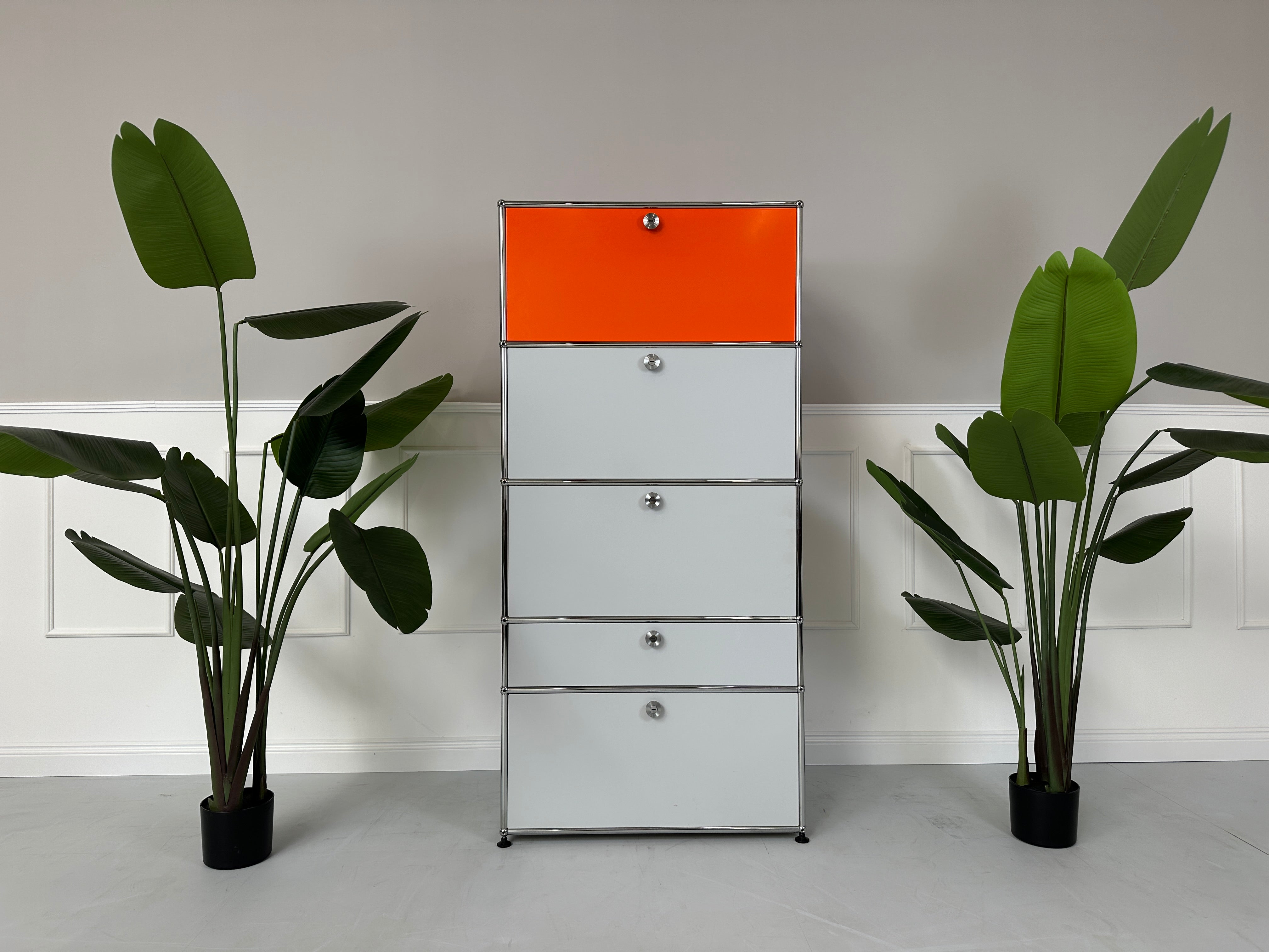 Gebrauchtes USM Haller Designer Regal in den Farben Orange und Grau vor einer Wand, stilvoll und modern eingerichtet.
