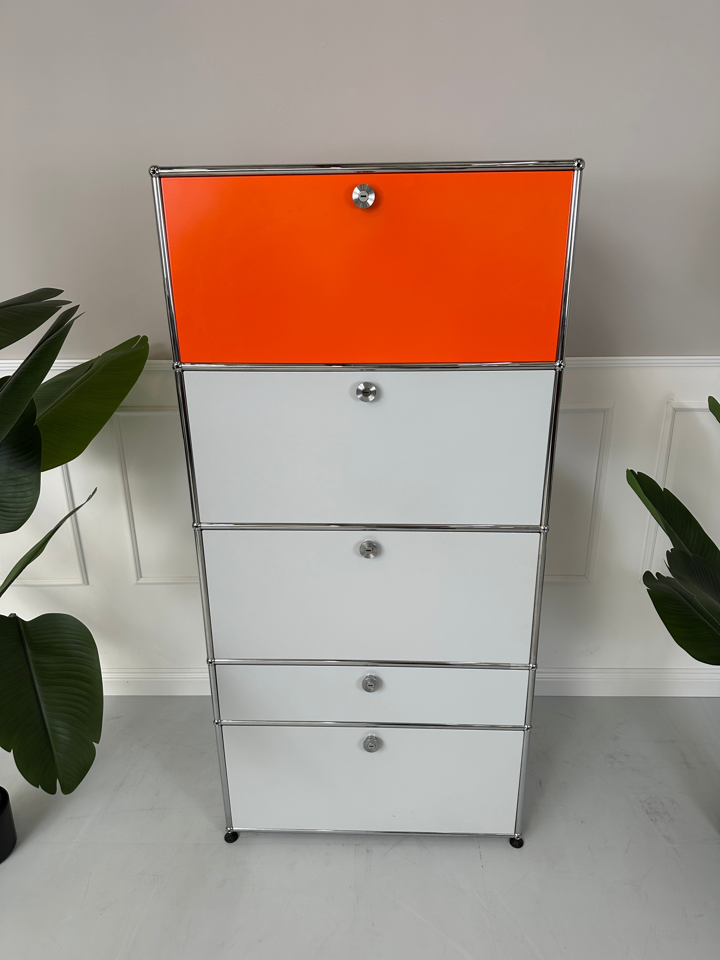 Gebrauchtes USM Haller Designer Regal in den Farben Orange und Grau vor einer Wand, stilvoll und modern eingerichtet.