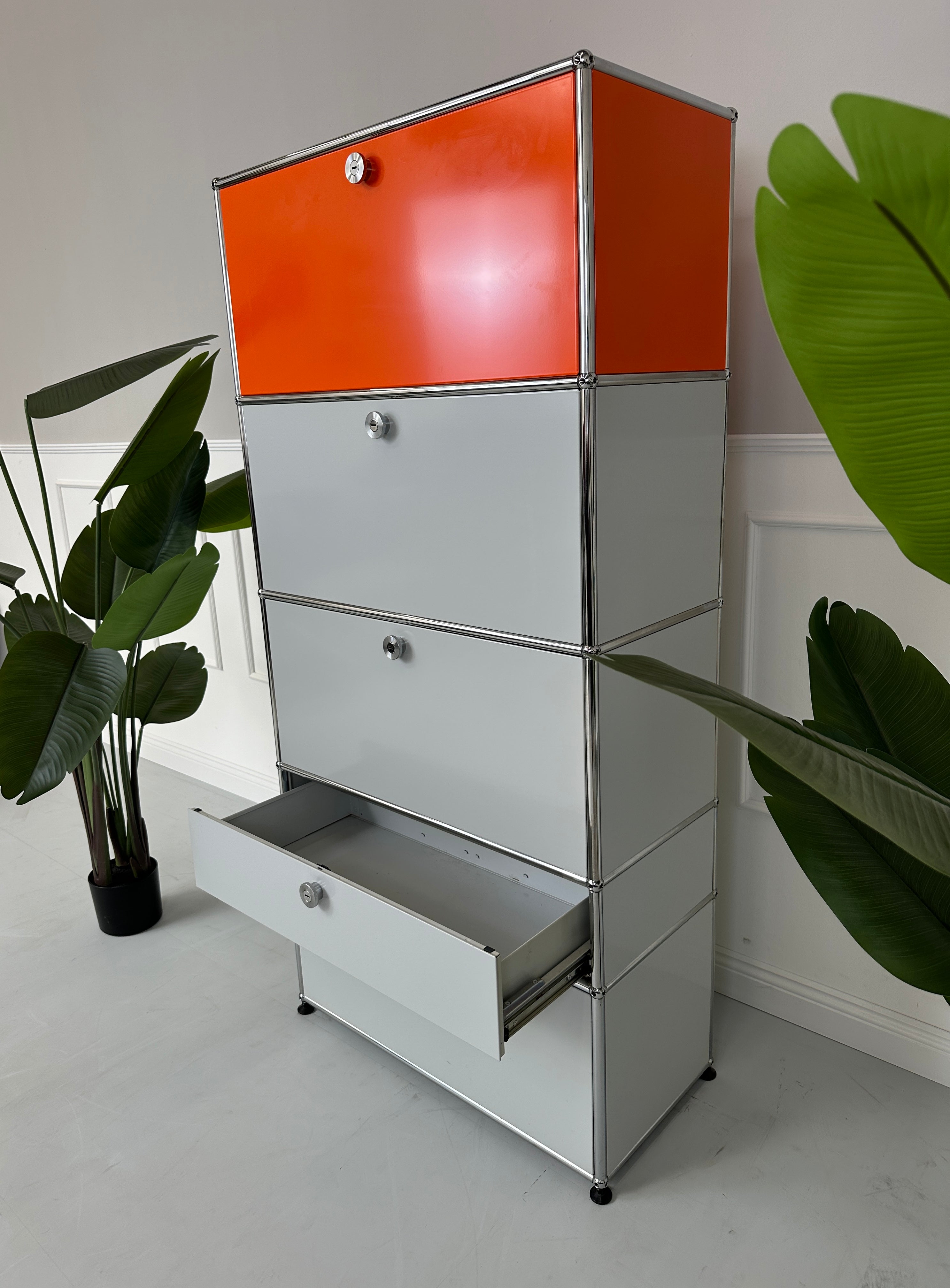 Gebrauchtes USM Haller Designer Regal in den Farben Orange und Grau vor einer Wand, stilvoll und modern eingerichtet.
