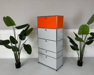 Gebrauchtes USM Haller Designer Regal in den Farben Orange und Grau vor einer Wand, stilvoll und modern eingerichtet.