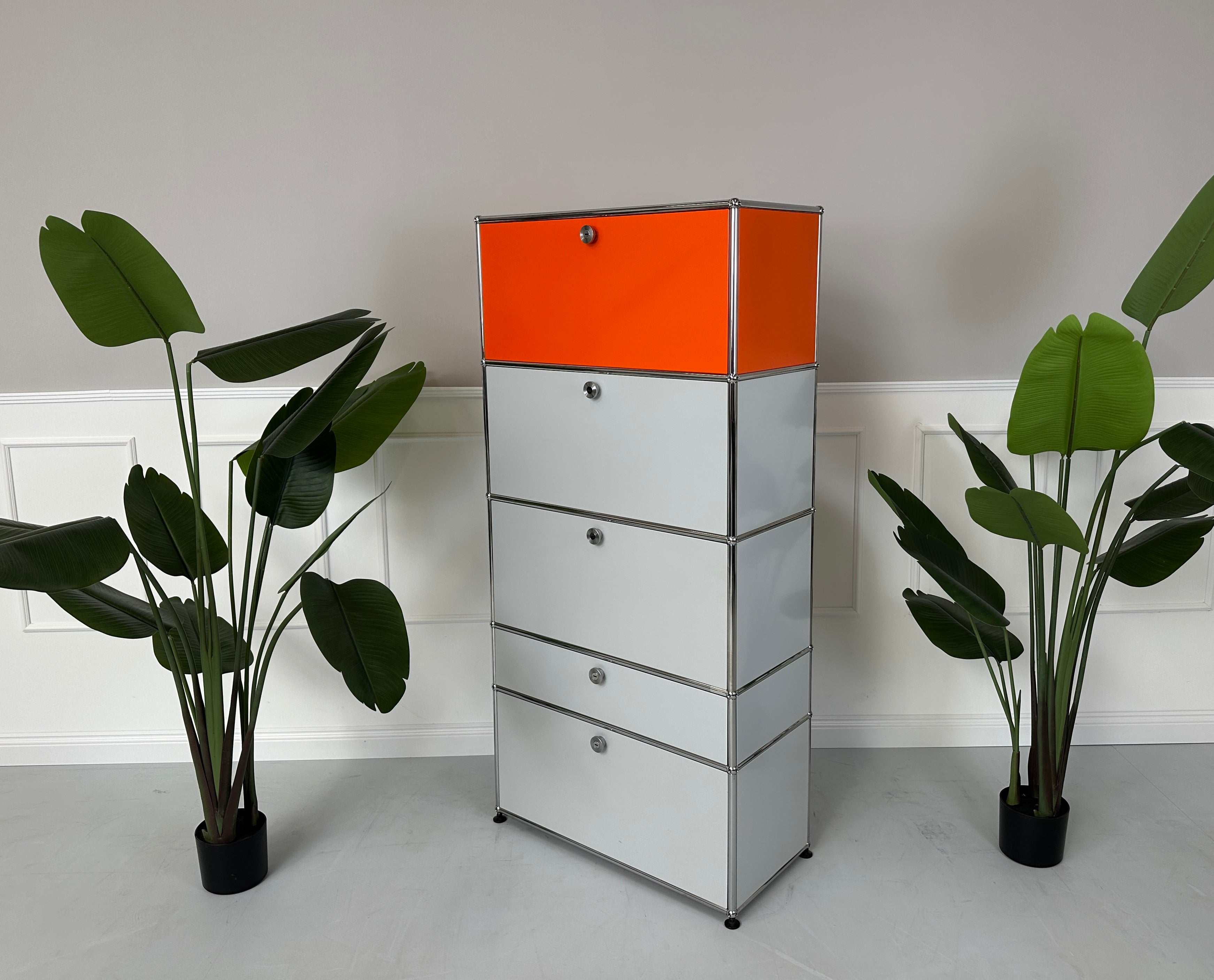 Gebrauchtes USM Haller Designer Regal in den Farben Orange und Grau vor einer Wand, stilvoll und modern eingerichtet.