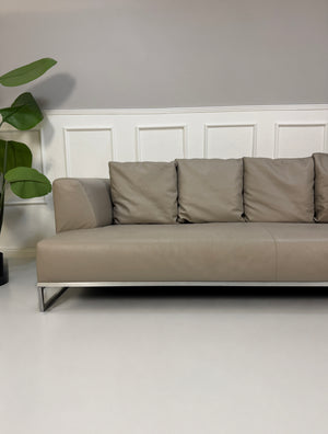 Gebrauchtes graues B&B Italia Solo Designer Leder Sofa vor einer Wand, stilvoll und modern eingerichtet.