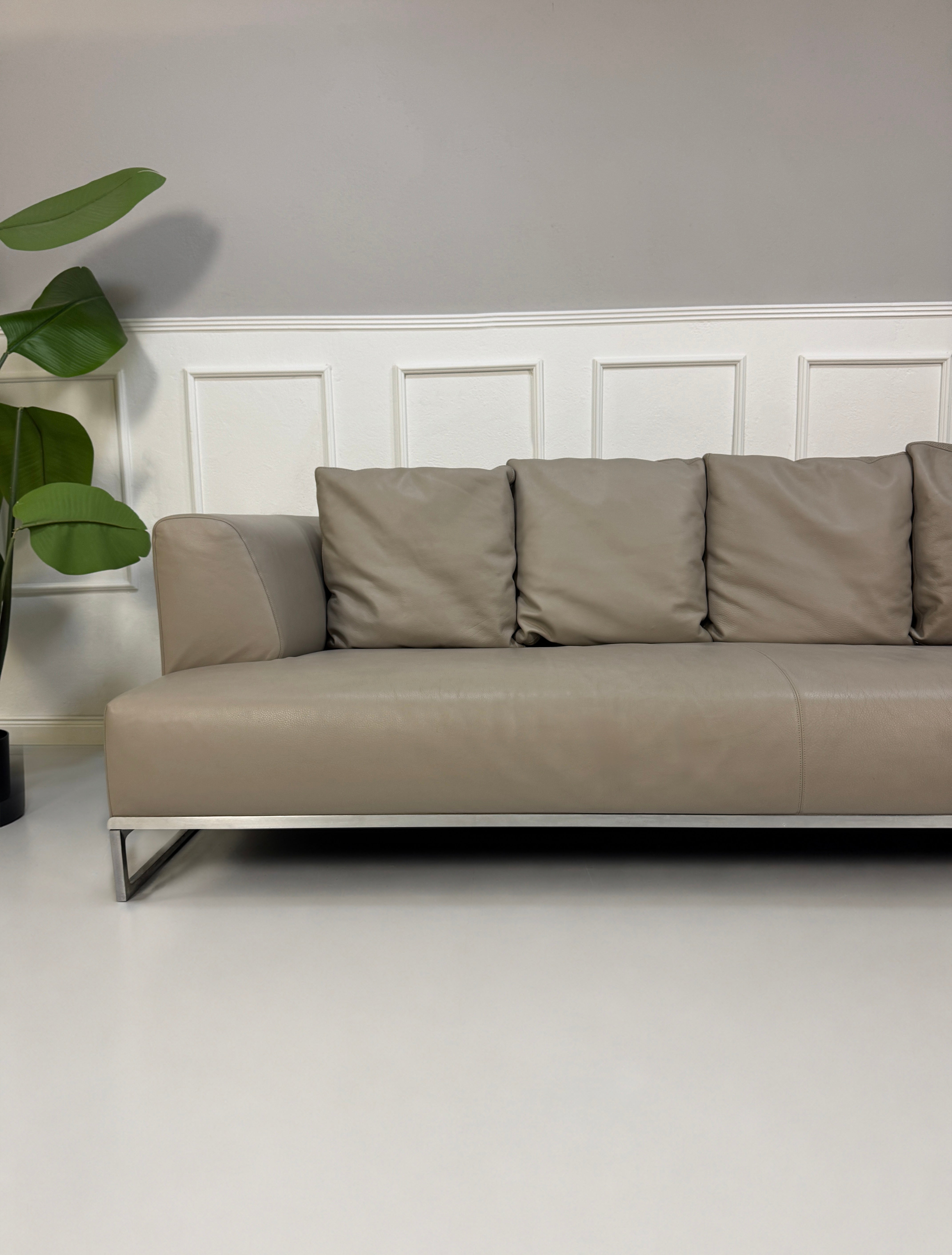 Gebrauchtes graues B&B Italia Solo Designer Leder Sofa vor einer Wand, stilvoll und modern eingerichtet.