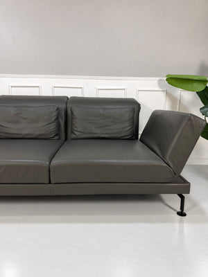 Gebrauchtes braunes Brühl Moule Large Designer Leder Sofa vor einer Wand, stilvoll und modern eingerichtet.